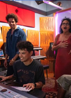 a producer smiling while two people behind him look impressed